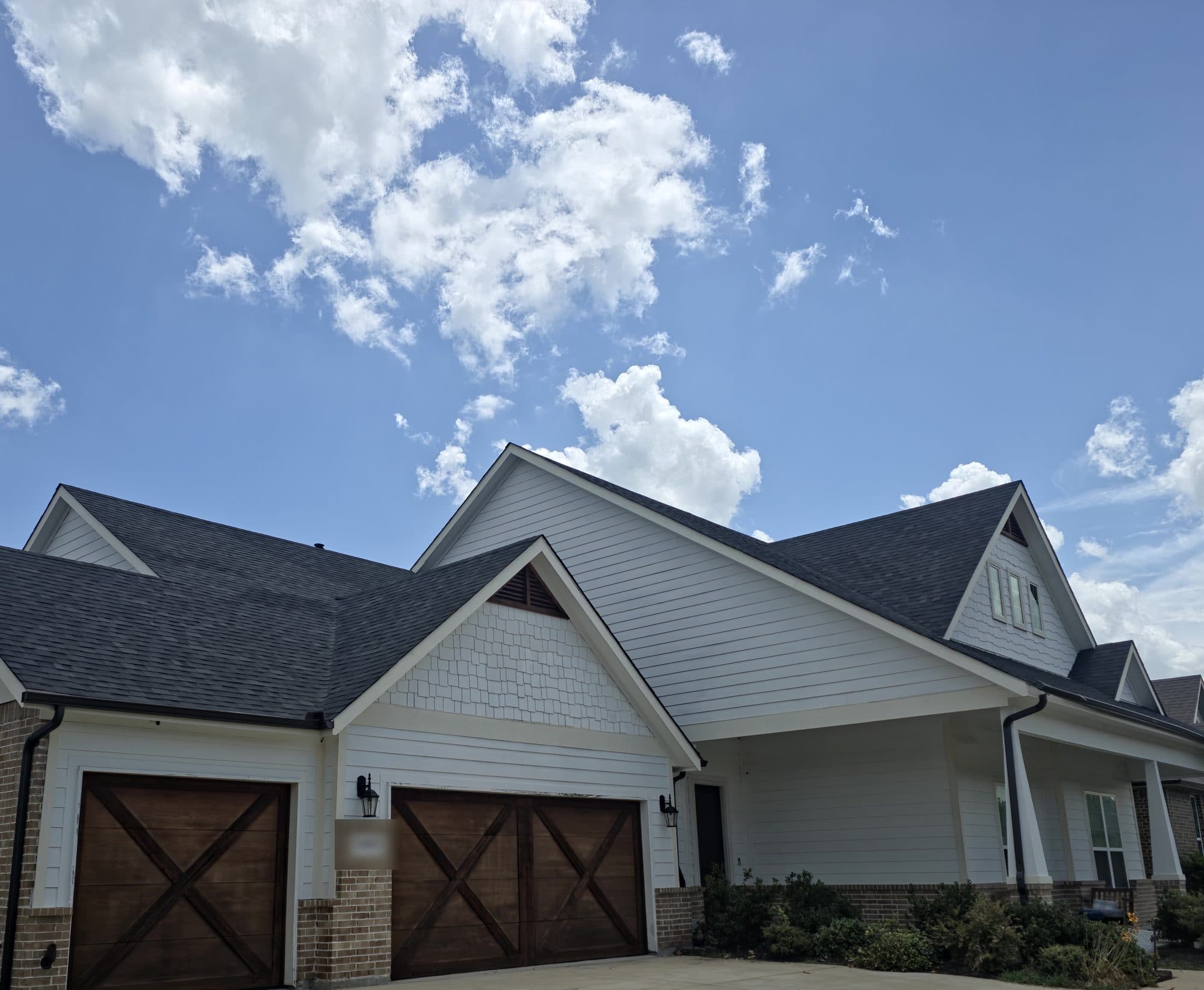 New charcoal shingle roof on a white farmhouse-style home