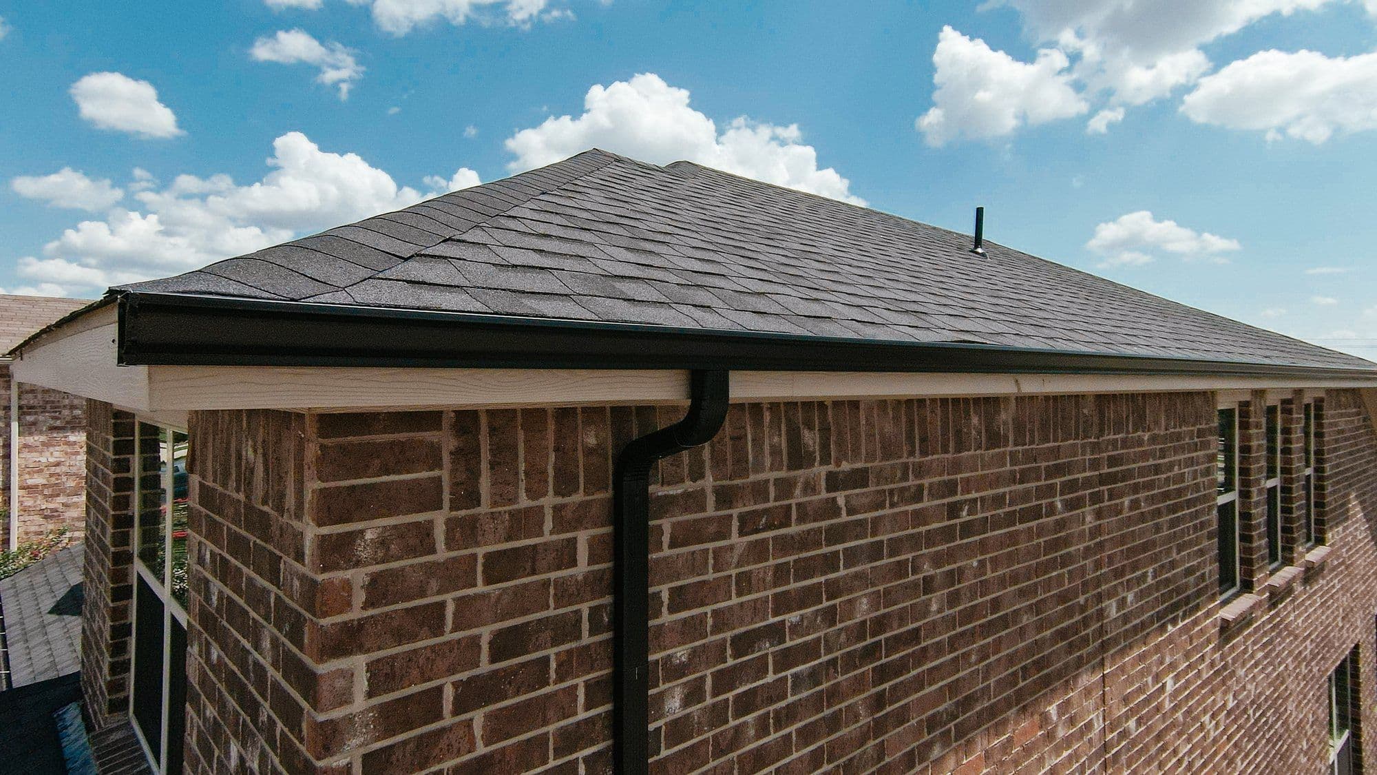 Finished roof edge with dark gutters on a brick home, Forney area