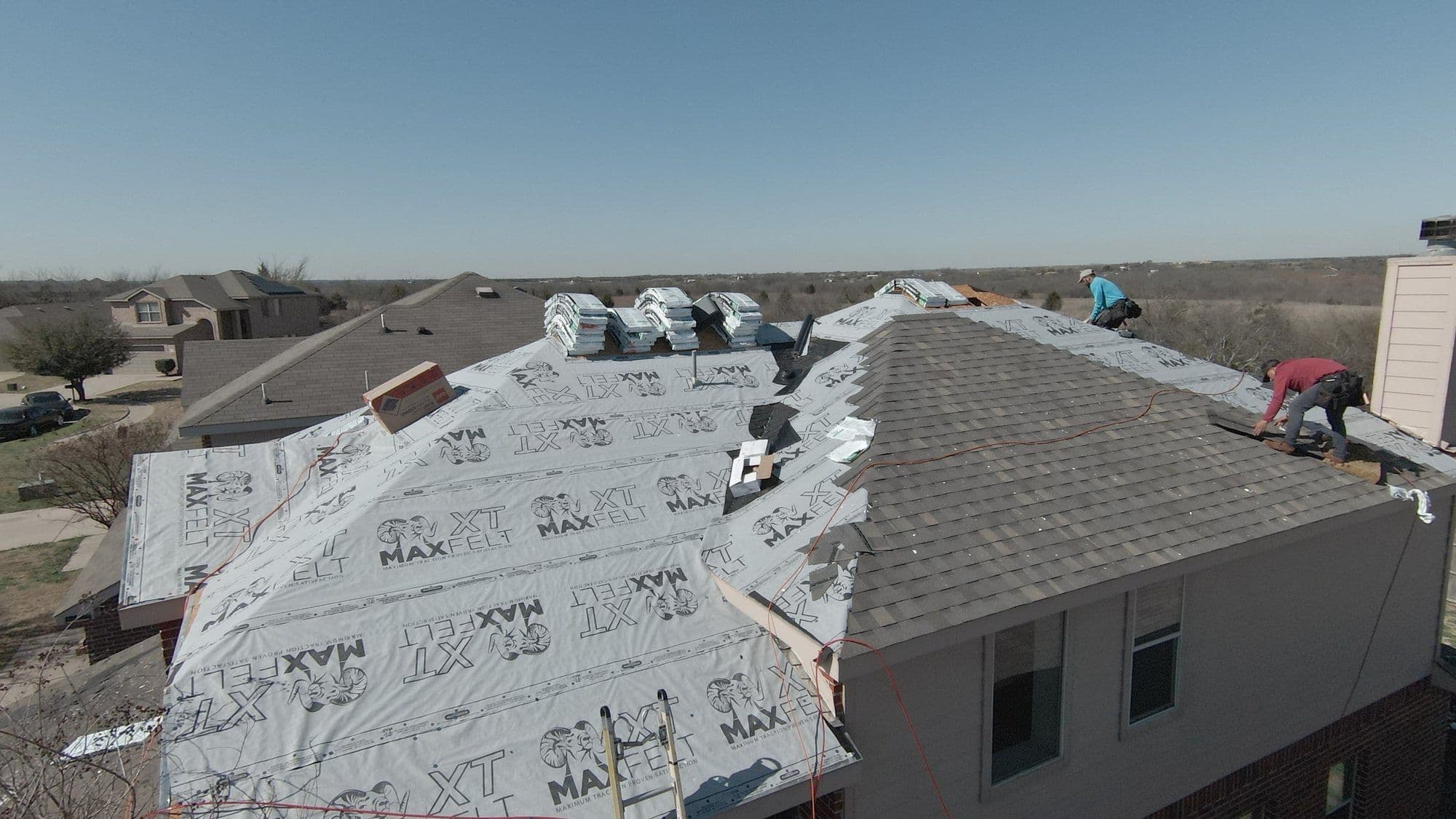 Shingle bundles staged on underlayment during a re-roof in the Forney area
