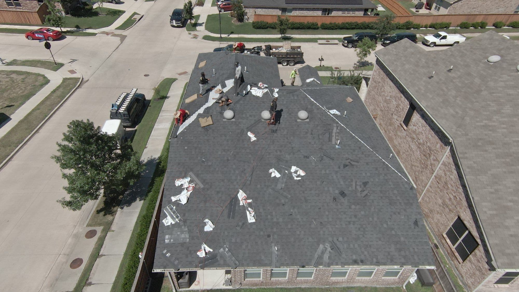Old shingles coming off during tear-off on a brick two-story in the Forney area